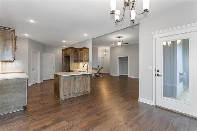 kitchen featuring dark wood-style flooring, light countertops, brown cabinets, tasteful backsplash, and pendant lighting