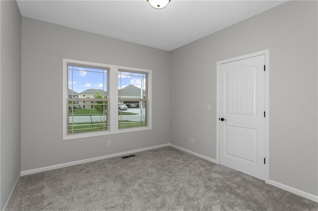 empty room with baseboards, visible vents, and light colored carpet