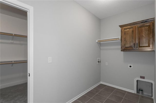 washroom with dark tile patterned flooring, cabinet space, electric dryer hookup, and baseboards