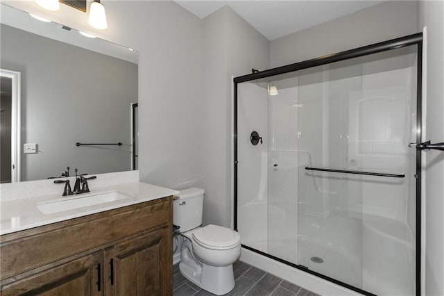 bathroom with a shower stall, toilet, and vanity