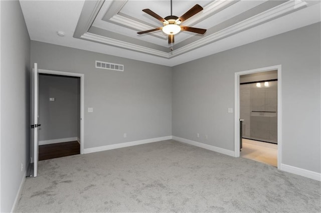 unfurnished bedroom with a tray ceiling, light colored carpet, visible vents, and baseboards