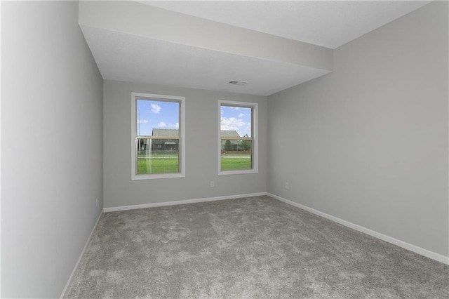 spare room featuring visible vents, light colored carpet, and baseboards