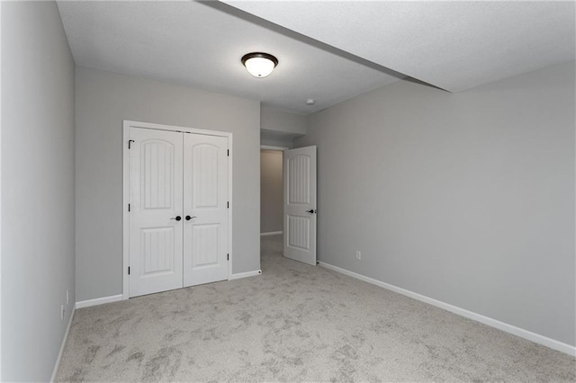 unfurnished bedroom featuring a closet, light carpet, and baseboards