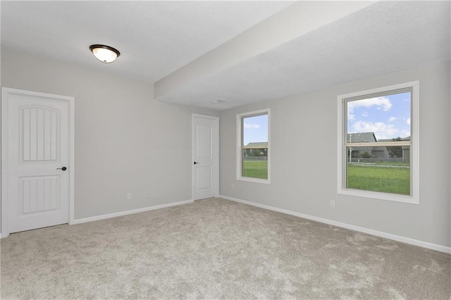 spare room featuring light carpet and baseboards