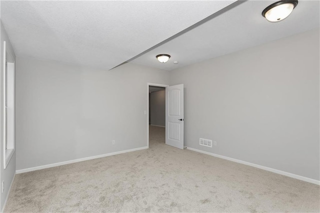 empty room featuring light colored carpet, visible vents, and baseboards