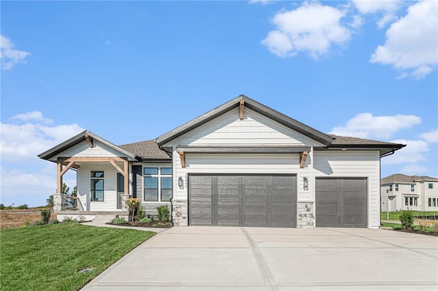 view of front of property with a garage, driveway, stone siding, a porch, and a front yard