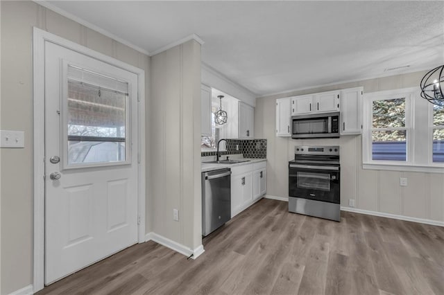 kitchen with appliances with stainless steel finishes, a chandelier, white cabinetry, and a sink