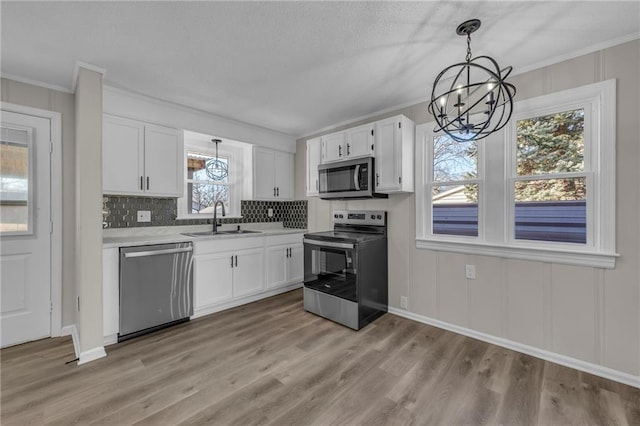 kitchen with stainless steel appliances, a sink, light countertops, and white cabinetry