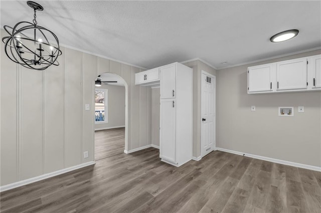 interior space featuring arched walkways, ornamental molding, dark wood-style floors, and baseboards