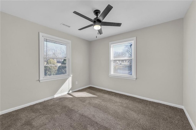 carpeted spare room featuring ceiling fan, visible vents, and baseboards