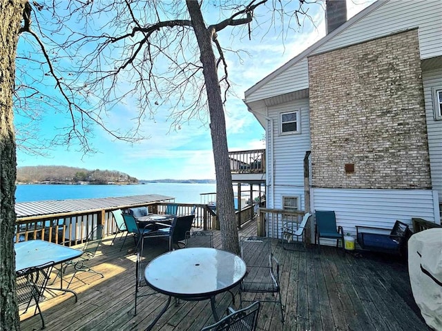 wooden deck featuring outdoor dining area and a water view