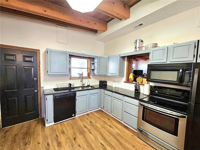 kitchen with dark countertops, visible vents, a sink, light wood-type flooring, and black appliances