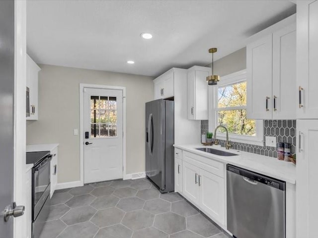 kitchen featuring appliances with stainless steel finishes, white cabinets, light countertops, and a sink