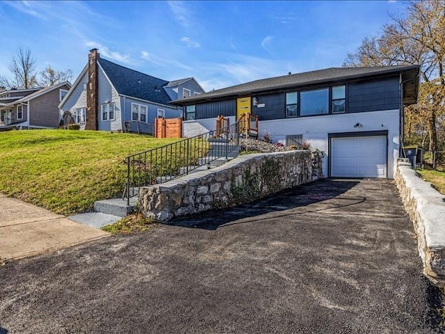 ranch-style home with aphalt driveway, a front lawn, and an attached garage