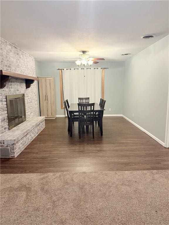 dining room with baseboards, a fireplace, visible vents, and dark wood finished floors