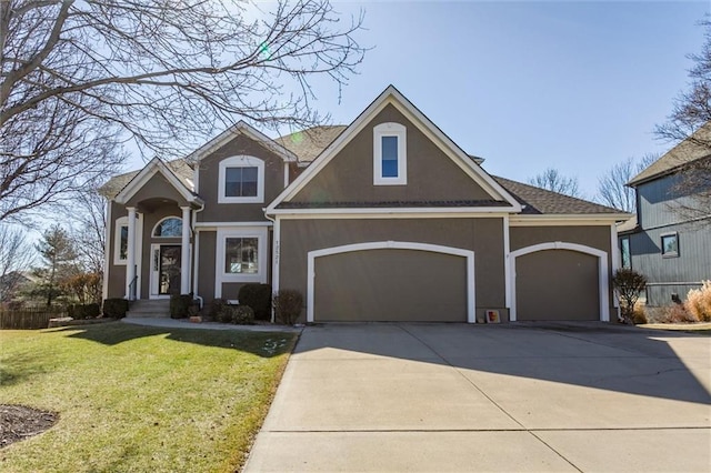 view of front of home with a garage, driveway, a front yard, and stucco siding