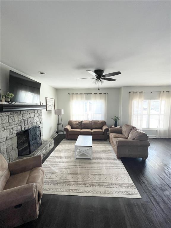 living room with dark wood-style floors, a fireplace, and ceiling fan