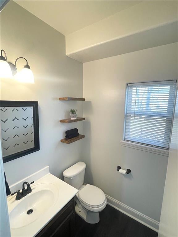 bathroom with toilet, baseboards, wood finished floors, and vanity