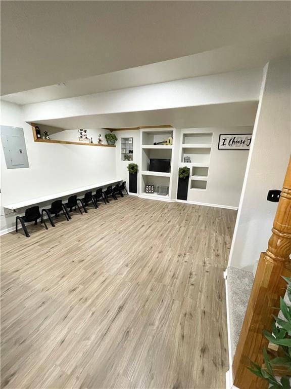 mudroom with built in features, electric panel, baseboards, and wood finished floors