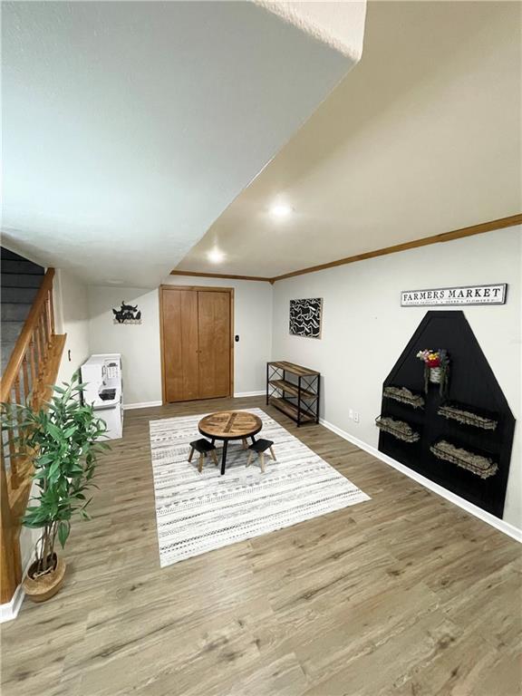 living area featuring ornamental molding, stairway, wood finished floors, and baseboards