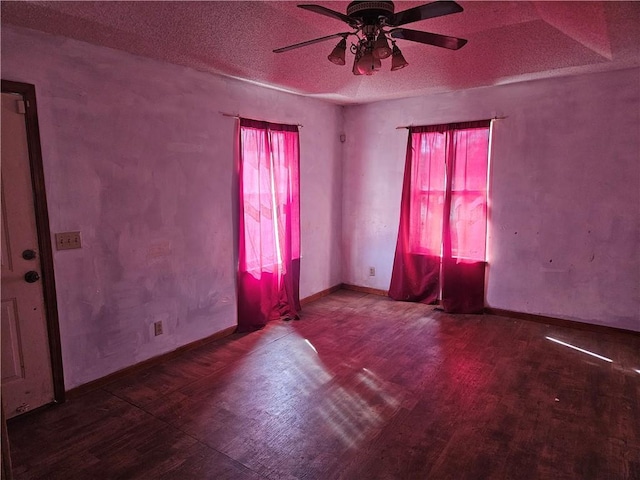 unfurnished room featuring a textured ceiling, ceiling fan, wood finished floors, and baseboards