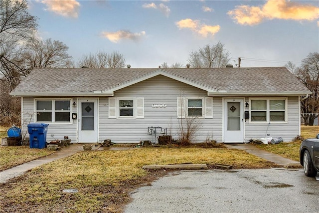 single story home featuring a shingled roof and a front lawn