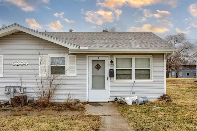 bungalow-style house with a shingled roof and a front yard