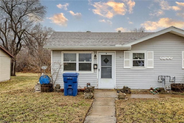 bungalow featuring roof with shingles and a front yard