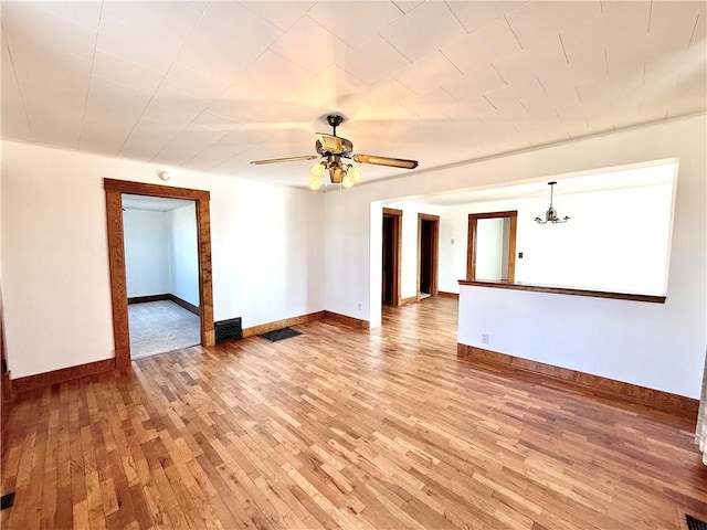 spare room with light wood-style flooring, baseboards, and ceiling fan with notable chandelier