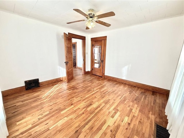 empty room with baseboards, light wood-style flooring, visible vents, and crown molding