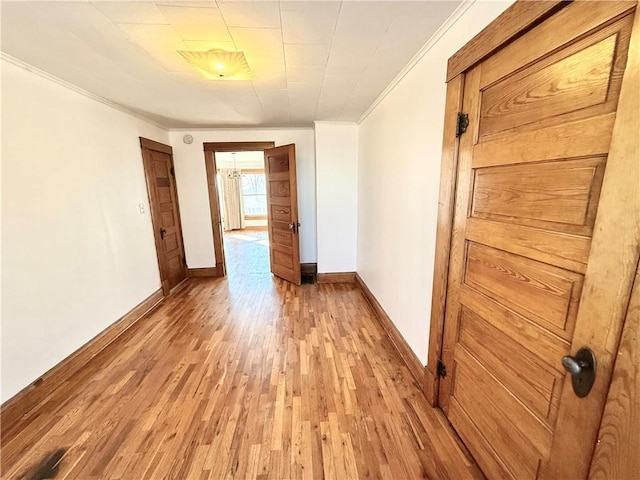 interior space featuring light wood-style floors, crown molding, and baseboards