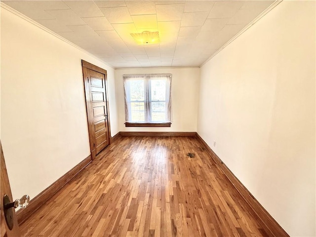 unfurnished room with crown molding, baseboards, and wood finished floors