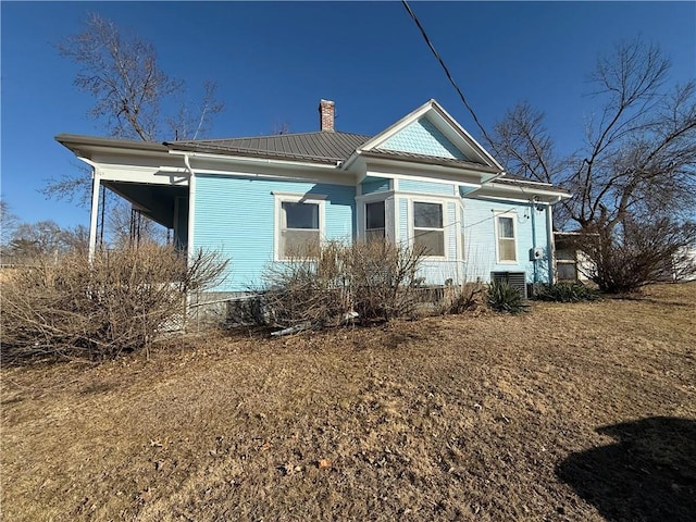 rear view of property with a chimney and central AC