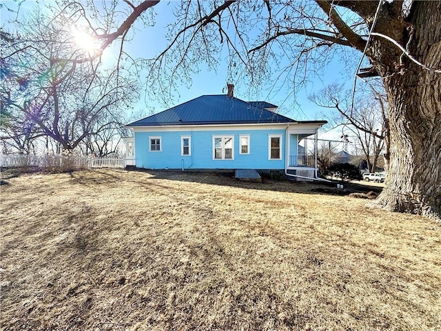 rear view of property featuring metal roof, fence, and a chimney