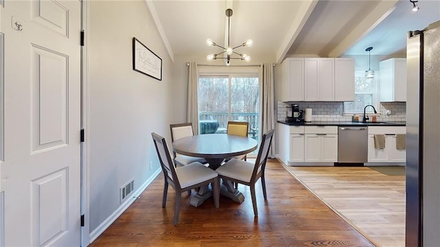 dining room featuring light wood-type flooring, lofted ceiling, a healthy amount of sunlight, and an inviting chandelier