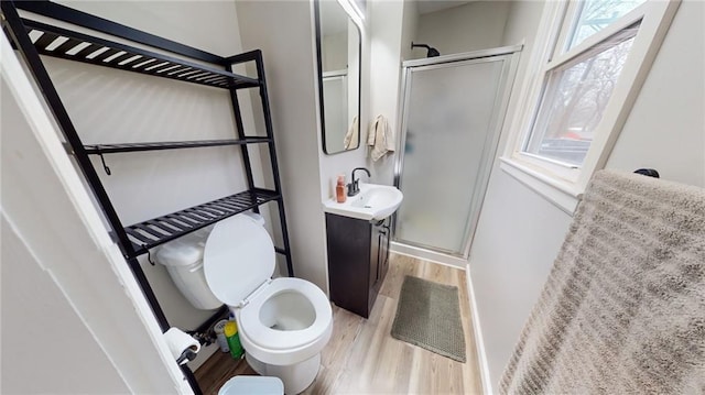 bathroom featuring a shower stall, toilet, vanity, and wood finished floors