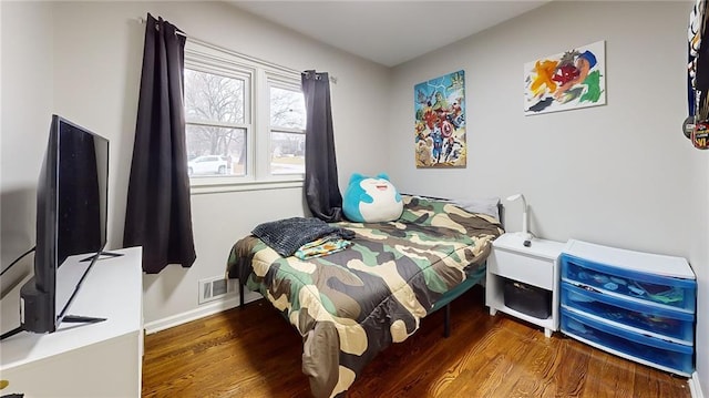 bedroom with baseboards, wood finished floors, and visible vents