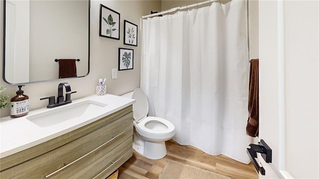 bathroom featuring toilet, vanity, wood finished floors, and curtained shower
