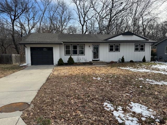 ranch-style home with board and batten siding, concrete driveway, fence, and an attached garage