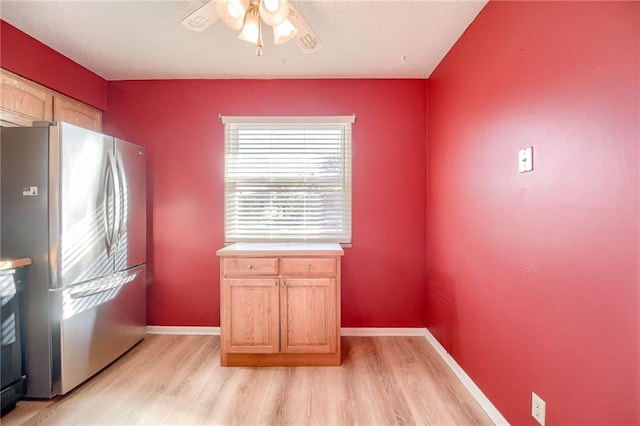 kitchen featuring light wood-type flooring, freestanding refrigerator, light countertops, and baseboards