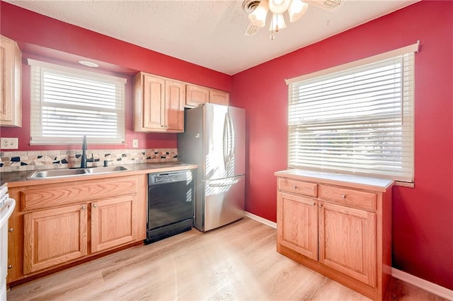 kitchen with black dishwasher, light brown cabinets, a sink, and freestanding refrigerator