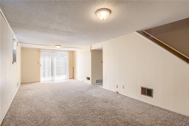 carpeted empty room with visible vents and a textured ceiling