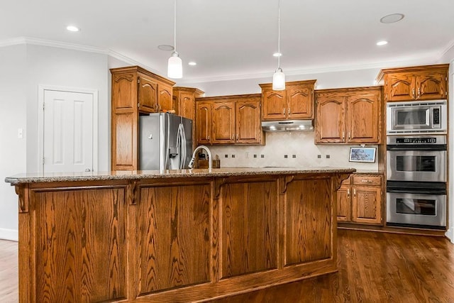 kitchen with under cabinet range hood, a breakfast bar area, stainless steel appliances, and ornamental molding