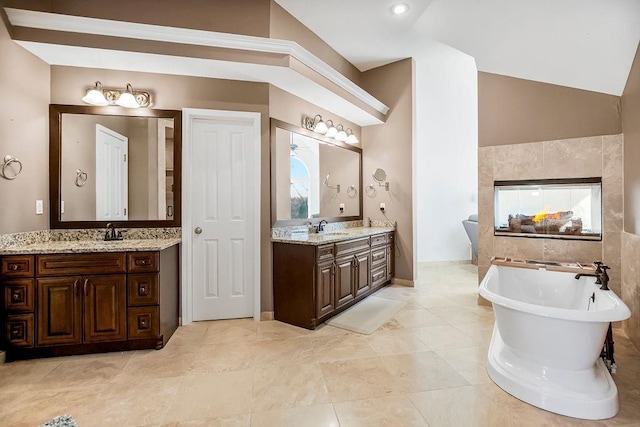 bathroom with vaulted ceiling, a soaking tub, two vanities, and a sink