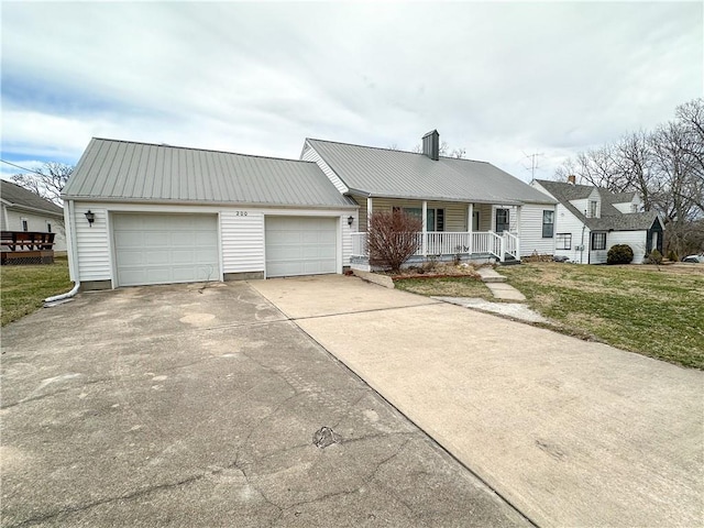 single story home with covered porch, metal roof, an attached garage, and a front yard