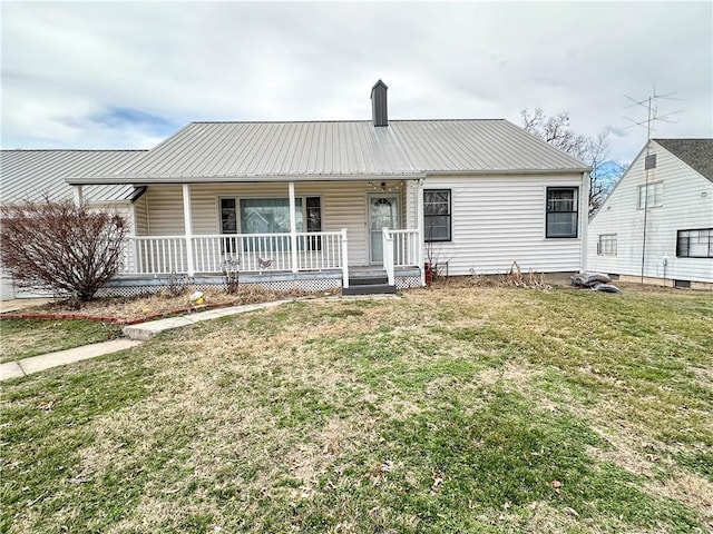 ranch-style home with a porch, metal roof, a chimney, and a front lawn