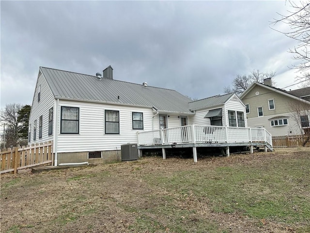 rear view of property featuring a yard, central AC, metal roof, fence, and a wooden deck