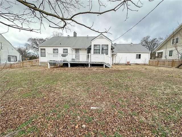 rear view of property with metal roof, fence, a yard, a wooden deck, and a chimney