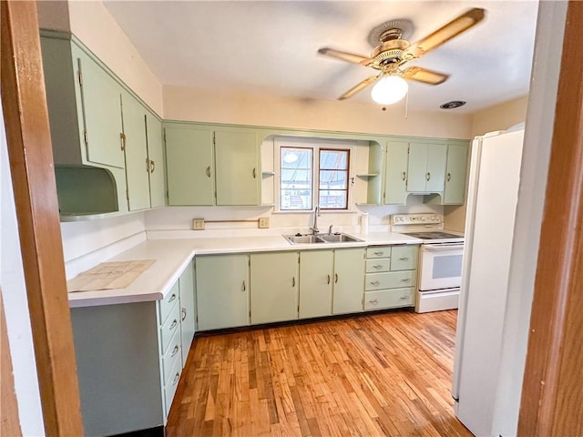 kitchen featuring light countertops, white appliances, green cabinetry, and a sink