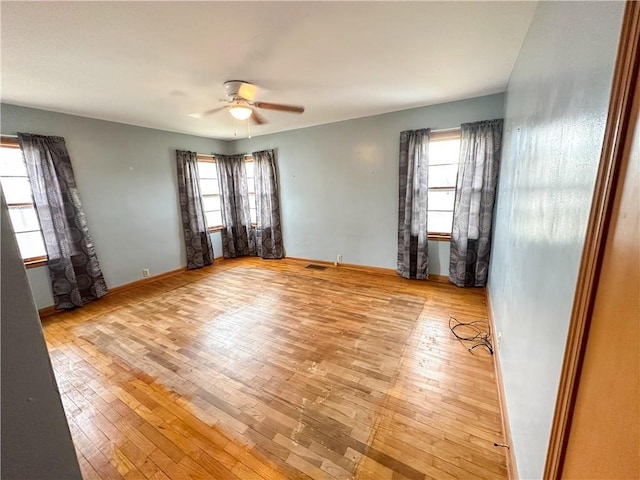 spare room with visible vents, a healthy amount of sunlight, ceiling fan, and light wood-style flooring